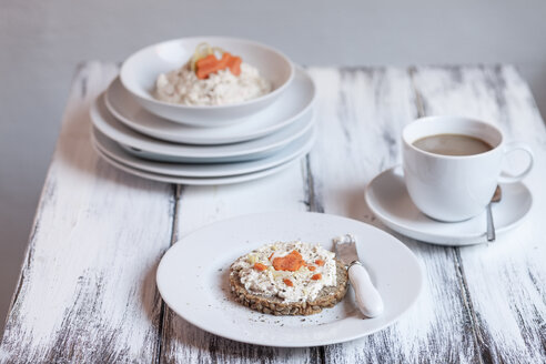 Deutsches dunkles Mehrkornbrot mit Frischkäse und Karotten, Tasse Kaffee auf Holztisch - SBDF000325