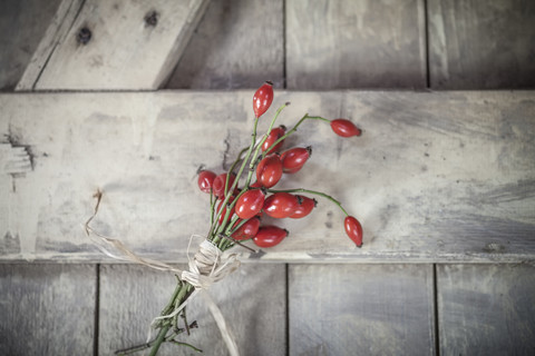 Blumenstrauß aus Hagebutten auf Holzbrett, Nahaufnahme, lizenzfreies Stockfoto