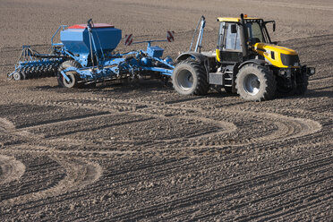 Deutschland, Bayern, Traktor mit Scheibenegge auf gepflügtem Boden - TC003666