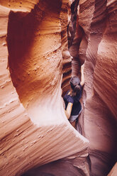 USA, Utah, Escalante, Peek-A-Boo and Spooky Slot Canyons, young woman climbing in gorge - MBEF000818
