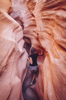 USA, Utah, Escalante, Peek-A-Boo and Spooky Slot Canyons, young woman climbing in gorge - MBEF000838