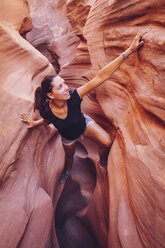USA, Utah, Escalante, Peek-A-Boo and Spooky Slot Canyons, young woman climbing in gorge - MBEF000822