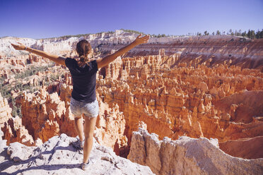 USA, Utah, junge Touristin, die zu den Hoodoo-Felsformationen im Bryce Canyon National Park hinunterblickt - MBEF000834