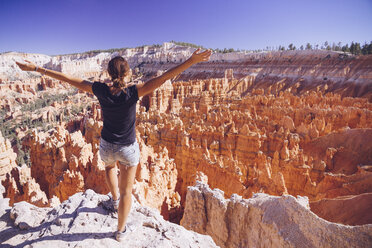 USA, Utah, young female tourist looking down to the Hoodoo rock formations in Bryce Canyon National Park - MBEF000834