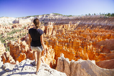 USA, Utah, junge Touristin, die zu den Hoodoo-Felsformationen im Bryce Canyon National Park hinunterblickt - MBEF000835