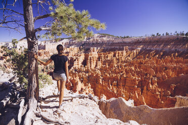 USA, Utah, young female tourist looking down to the Hoodoo rock formations in Bryce Canyon National Park - MBEF000836