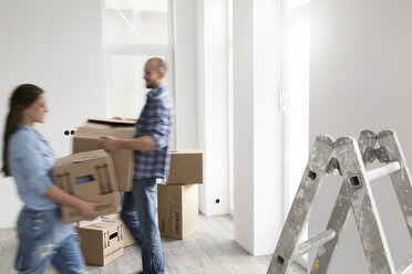 Young couple moving into new home, carrying cardboard boxes - FKF000340