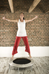 Germany, Bavaria, Woman jumping on trampoline - RNF001293