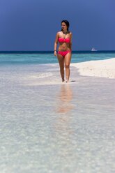 Malediven, Junge Frau im Bikini geht im flachen Wasser spazieren - AMF001215