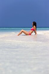 Maldives, Young woman in bikini sitting in shallow water - AMF001213