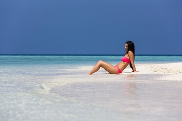 Malediven, Junge Frau im Bikini sitzt im flachen Wasser - AMF001212
