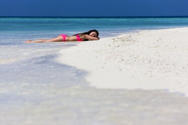 Maldives, Young woman in bikini lying in shallow water - AMF001211