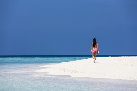 Malediven, Junge Frau im Bikini geht am Strand spazieren, lizenzfreies Stockfoto