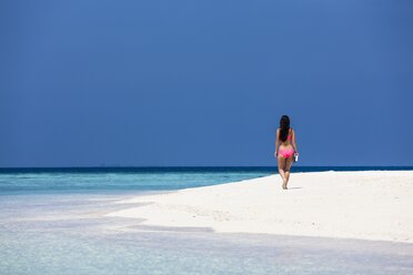 Malediven, Junge Frau im Bikini geht am Strand spazieren - AMF001209