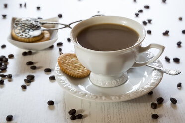 Tasse Kaffee, Kekse und verstreute Kaffeebohnen auf Holztisch - SARF000135