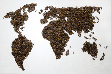 Weltkarte in Form von Kaffeebohnen auf weißem Tisch - SARF000139