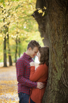 Young couple leaning against tree trunk - BGF000019