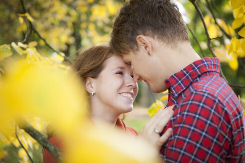 Glückliches junges Paar, das sich in einem Park küsst - BGF000021