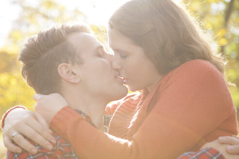 Glückliches junges Paar, das sich in einem Park küsst - BGF000023