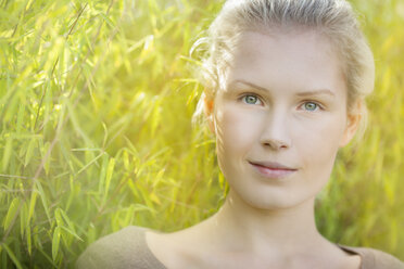 Portrait of smiling young woman in front of bamboo, close-up - BGF000047