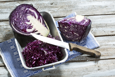 Rotkohl, Küchenmesser und Küchenhandtuch auf Holztisch, lizenzfreies Stockfoto