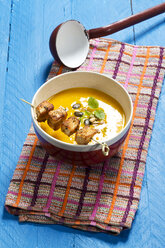 Creamed pumpkin soup in bowl with chicken skewer - MAEF007373