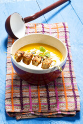 Creamed pumpkin soup in bowl with chicken skewer - MAEF007375