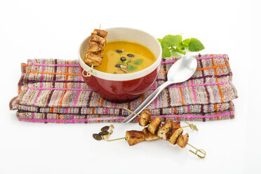 Creamed pumpkin soup in bowl with chicken skewer - MAEF007381