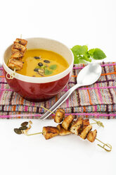 Creamed pumpkin soup in bowl with chicken skewer - MAEF007382
