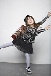 Smiling girl with accordion standing on one leg - FSF000315