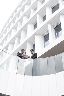 Polen, Warzawa, zwei Geschäftsleute mit Tablet-Computer stehen vor einem Hotel - MLF000250