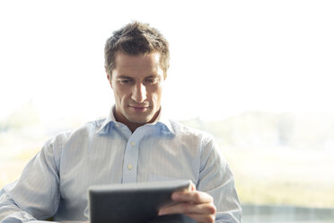 Poland, Warzawa, businessman using tablet computer at hotel lounge - MLF000365