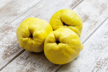 Three quinces (Cydonia oblonga) on wooden table - CSF020327