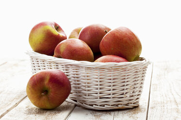 Äpfel (Malus) in weißem Korb auf Holztisch - CSF020345