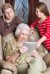 ältere Frau und zwei Urgroßtöchter vor einem Tablet-Computer - ABAF001083