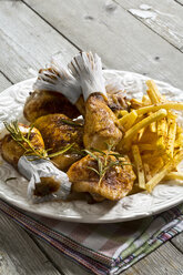 Chicken drums with french fries on plate - MAEF007389
