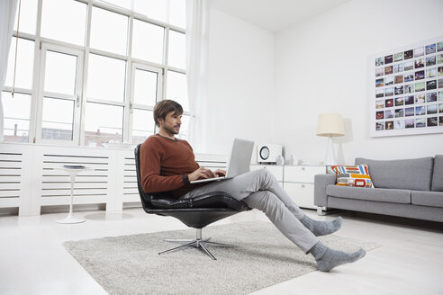 Deutschland, München, Mann benutzt Laptop zu Hause - RBF001411