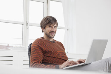 Germany, Munich, Man using laptop at home - RBF001414