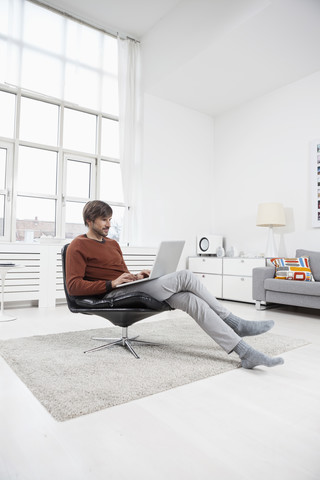 Deutschland, München, Mann benutzt Laptop zu Hause, lizenzfreies Stockfoto