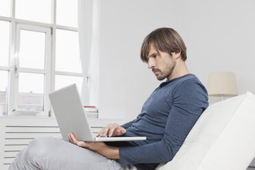 Germany, Munich, Man using laptop at home - RBF001416