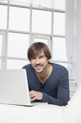 Germany, Munich, Man using laptop at home - RBF001419