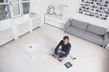 Deutschland, München, Mann sitzt auf dem Boden im Wohnzimmer - RBF001420