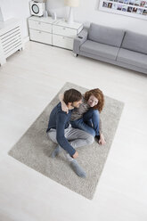 Deutschland, München, Paar sitzt auf dem Boden im Wohnzimmer - RBF001430