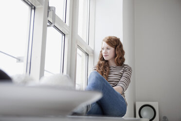 Germany, Munich, Woman sitting on window sill - RBF001435