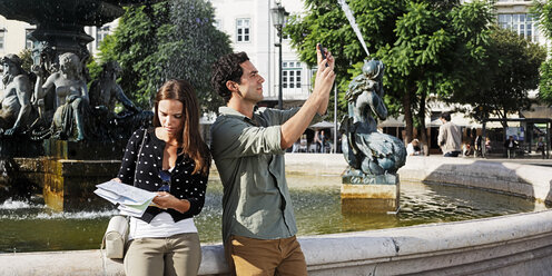 Portugal, Lisboa, Baixa, Rossio, Praca Dom Pedro IV, junges Paar mit Stadtplan und Smartphone vor einem Springbrunnen - BIF000041