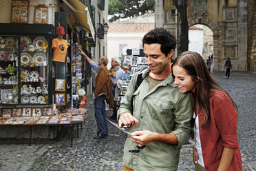 Portugal, Lisboa, Baixa, Rossio, young couple looking at postcard - BI000023