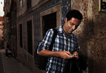 Portugal, Lisboa, Bairro Alto, junger Mann schaut auf sein Mobiltelefon - BIF000069