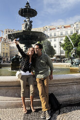 Portugal, Lisboa, Baixa, Rossio, Praca Dom Pedro IV, young couple photographing themself in front of a fountain - BIF000012