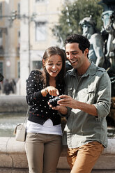 Portugal, Lisboa, Baixa, Rossio, Praca Dom Pedro IV, lächelndes junges Paar beim Betrachten der eigenen Bilder - BIF000071