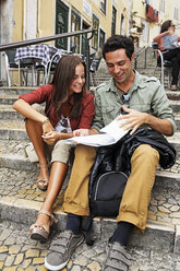 Portugal, Lisboa, Carmo, Calcada du Duque, young couple with city map sitting at stairs - BI000008